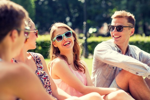 41728728 - friendship, leisure, summer and people concept - group of smiling friends outdoors sitting on grass in park