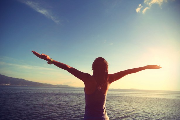 49955651 - young cheering woman jogger open arms at sunrise seaside,vintage effect