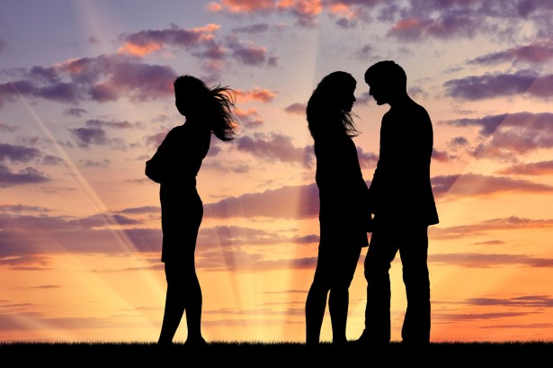 52301967 - concept of betrayal and treason. silhouette of a lonely woman near loving couple at sunset